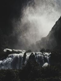 Scenic view of waterfall in forest against sky