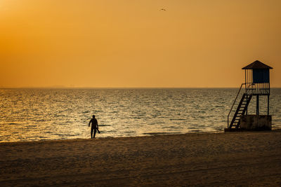 Silhouette person on beach against sky during sunset