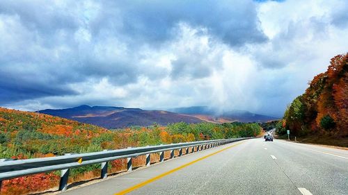 Country road against cloudy sky