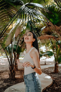 Full length of woman standing by palm tree