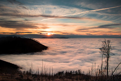 Last rays of the sun cross the clouds and go behind a high mountain and put the earth in the dark