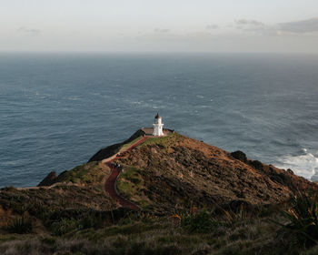 Lighthouse on rock by sea against sky