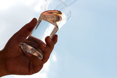 Close-up of hand holding drink against sky