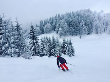 Man skiing on snowy mountain against sky
