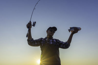 Low angle view of man photographing against clear sky