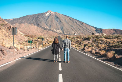 Rear view of people on road against mountain range