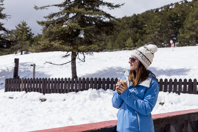 Woman standing on snow against trees in winter