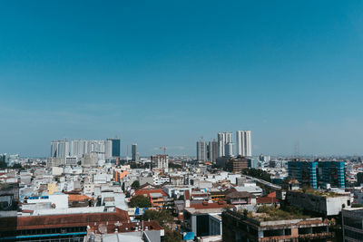 High angle view of buildings in city against blue sky