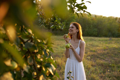 Full length portrait of woman standing against plants