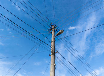 Low angle view of electricity pylon against blue sky