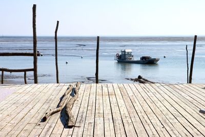 Wooden posts in sea against clear sky