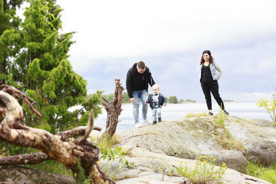 Young couple standing by tree against sky