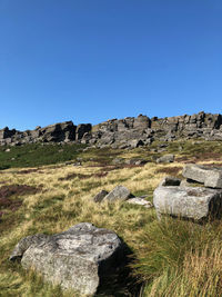 Rocks on field against clear blue sky