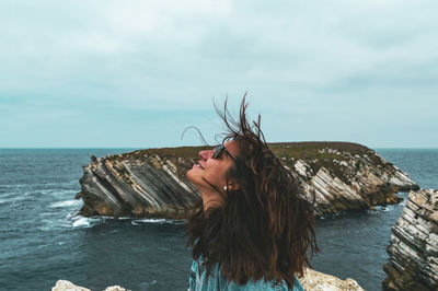 Side view of woman by sea against sky