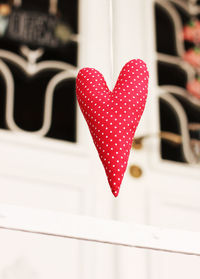 Low angle view of red polka dotted heart shape decoration hanging outdoors