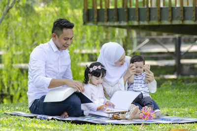 Full length of father and daughter sitting on grass