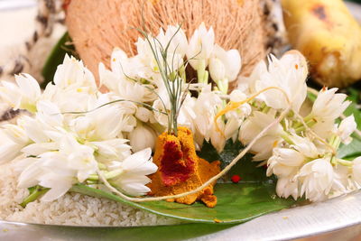 Close-up of flowers and religious equipment in plate