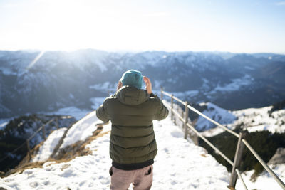 Rear view of man standing on snowcapped mountain