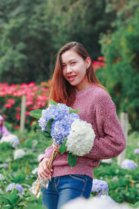 Beautiful young woman standing by flowering plant