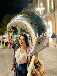 Rear view of woman with balloons while standing in city