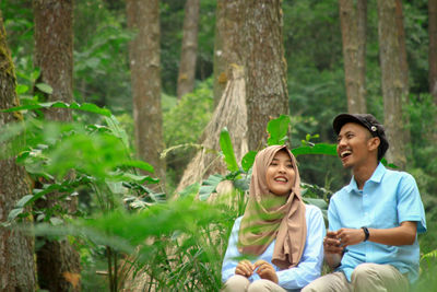 Smiling young couple sitting at forest