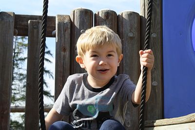 Cute boy playing on play equipment at park