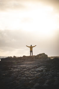 Rear view of man standing on mountain against sky during sunset
