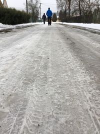 Rear view of man walking on snow covered road