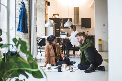 Smiling architects discussing while female entrepreneur working in background at home office