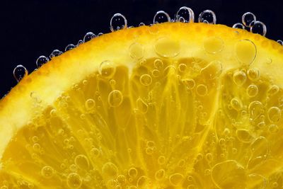 Close-up of yellow drink in water against black background