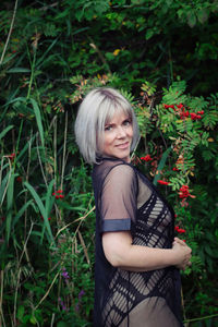 Portrait of young woman standing against plants