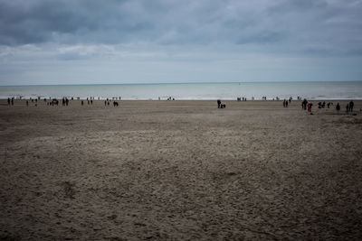 Scenic view of beach against cloudy sky