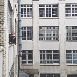 Portrait of woman waving hand through building window