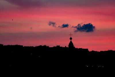 Silhouette of temple against building during sunset