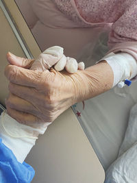 Midsection of senior patient holding hand of doctor