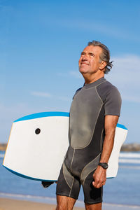 Rear view of man standing by sea against sky