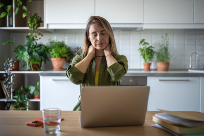 Young woman using laptop while sitting on table