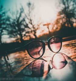 Close-up of sunglasses against sky during sunset