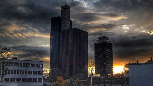 Low angle view of skyscrapers against cloudy sky during sunset
