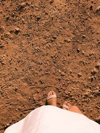 Low section of woman standing on sand