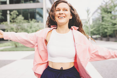 Portrait of young woman standing against wall
