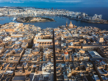 High angle view of city by sea against sky