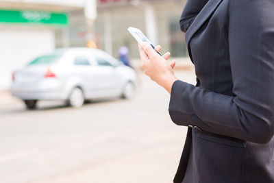 Midsection of man using mobile phone in city