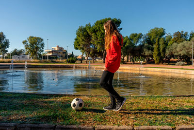 Rear view of young woman with dog on river