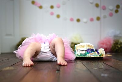 Baby girl lying on hardwood floor at home