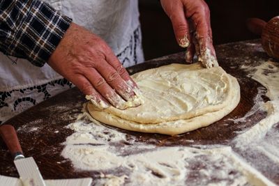 Midsection of man preparing dough in kitchen