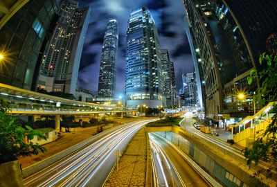 Light trails on road amidst illuminated buildings in city at night