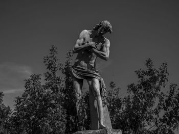 Low angle view of statue against trees against sky
