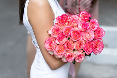 Midsection of woman holding rose bouquet