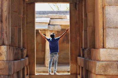 Rear view of man with arms raised standing on doorway